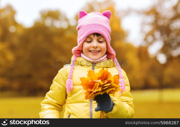 autumn, childhood, happiness and people concept - happy beautiful little girl with maple leaves bunch outdoors