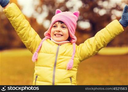 autumn, childhood, happiness and people concept - happy little girl with raised hands having fun outdoors