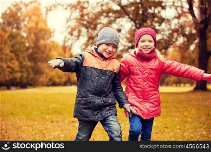 autumn, childhood, leisure and people concept - group of happy little children running and playing planes outdoors
