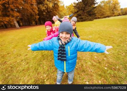 autumn, childhood, leisure and people concept - group of happy little children playing planes outdoors