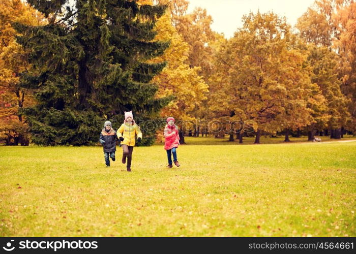 autumn, childhood, leisure and people concept - group of happy little kids playing tag game and running in park outdoors
