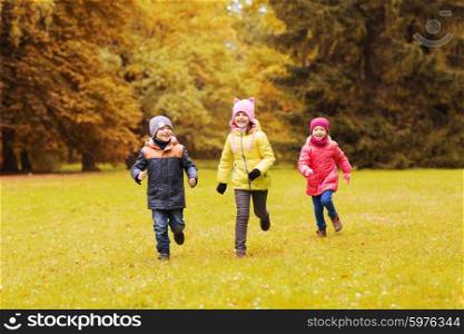 autumn, childhood, leisure and people concept - group of happy little kids playing tag game and running in park outdoors