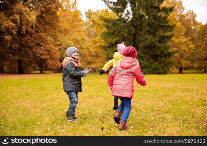 autumn, childhood, leisure and people concept - group of happy little kids playing tag game and having fun in park outdoors