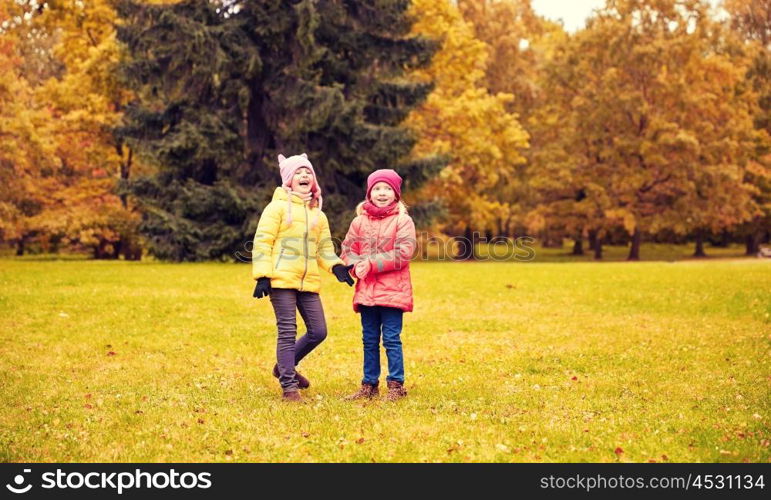 autumn, childhood, leisure and people concept - two happy little girls in park