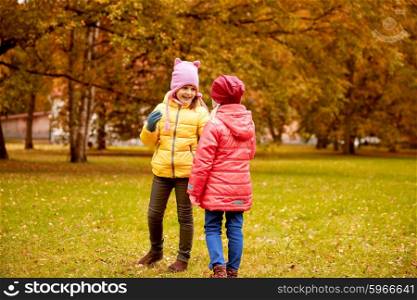autumn, childhood, leisure and people concept - two happy little girls in park