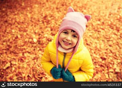 autumn, childhood, nature and people concept - happy little girl over fallen leaves in park