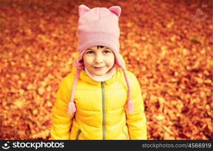 autumn, childhood, nature and people concept - happy little girl over fallen leaves in park