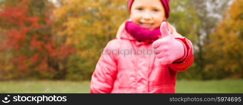 autumn, childhood, season, gesture and people concept - close up of happy little girl showing thumbs up outdoors over natural background