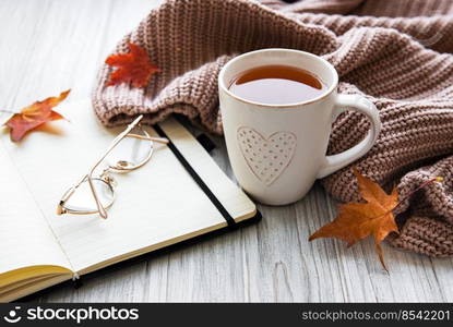 Autumn composition. Cup of tea, women fashion sweater, dried leaves,  notebook. Autumn, fall concept. 