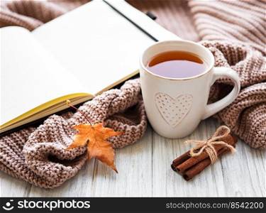 Autumn composition. Cup of tea, women fashion sweaters, dried leaves and notebook. Autumn, fall concept.