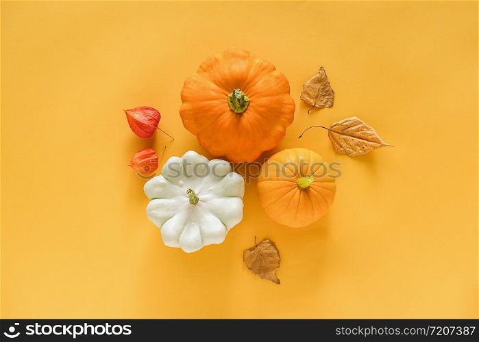Autumn composition. Fresh three pattypan squash, pumpkin and autumn leaves herbarium on yellow background with copy space. Top view Flat lay Template for your design, invitation, greeting card.. Autumn composition. Fresh three pattypan squash, pumpkin and autumn leaves herbarium on yellow background with copy space. Top view Flat lay Template for your design, invitation, greeting card