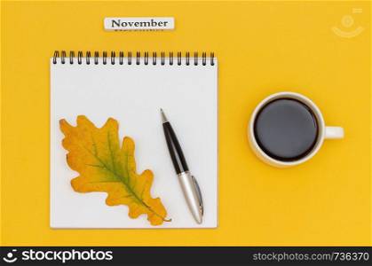 Autumn composition. Text November Coffee Cup, open notepad with pen and yellow oak leaf on yellow paper background. Top view Flat lay Mockup.. Autumn composition. Text November Coffee Cup, open notepad with pen and yellow oak leaf on yellow paper background. Top view Flat lay Mockup