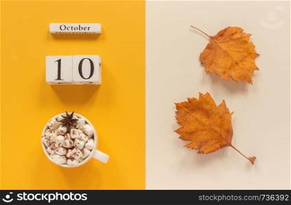 Autumn composition. Wooden calendar October 10 , cup of cocoa with marshmallows and yellow autumn leaves on yellow beige background. Top view Flat lay Mockup Concept Hello September.. Autumn composition. Wooden calendar October 10, cup of cocoa with marshmallows and yellow autumn leaves on yellow beige background. Top view Flat lay Mockup Concept Hello September