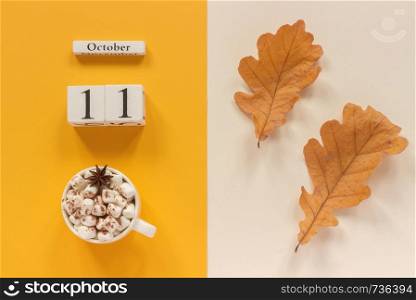 Autumn composition. Wooden calendar October 11 , cup of cocoa with marshmallows and yellow autumn leaves on yellow beige background. Top view Flat lay Mockup Concept Hello September.. Autumn composition. Wooden calendar October 11, cup of cocoa with marshmallows and yellow autumn leaves on yellow beige background. Top view Flat lay Mockup Concept Hello September