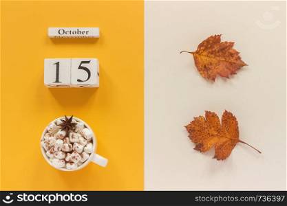 Autumn composition. Wooden calendar October 15, cup of cocoa with marshmallows and yellow autumn leaves on yellow beige background. Top view Flat lay Mockup Concept Hello September.. Autumn composition. Wooden calendar October 15, cup of cocoa with marshmallows and yellow autumn leaves on yellow beige background. Top view Flat lay Mockup Concept Hello September