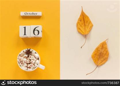 Autumn composition. Wooden calendar October 16, cup of cocoa with marshmallows and yellow autumn leaves on yellow beige background. Top view Flat lay Mockup Concept Hello September.. Autumn composition. Wooden calendar October 16, cup of cocoa with marshmallows and yellow autumn leaves on yellow beige background. Top view Flat lay Mockup Concept Hello September