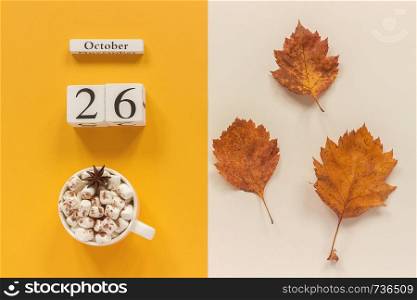 Autumn composition. Wooden calendar October 26, cup of cocoa with marshmallows and yellow autumn leaves on yellow beige background. Top view Flat lay Mockup Concept Hello September.. Autumn composition. Wooden calendar October 26, cup of cocoa with marshmallows and yellow autumn leaves on yellow beige background. Top view Flat lay Mockup Concept Hello September