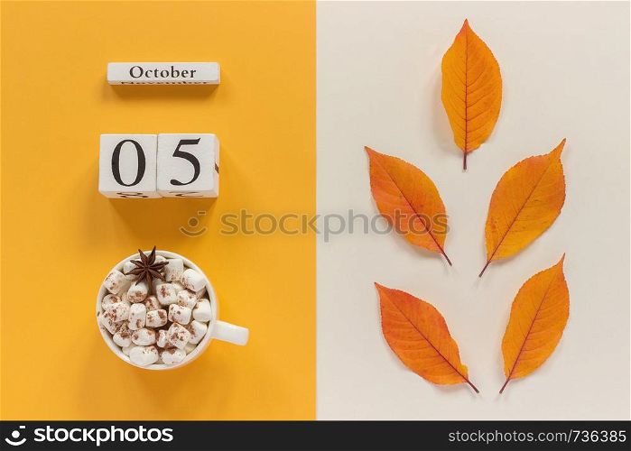 Autumn composition. Wooden calendar October 5, cup of cocoa with marshmallows and yellow autumn leaves on yellow beige background. Top view Flat lay Mockup Concept Hello September.. Autumn composition. Wooden calendar October 5, cup of cocoa with marshmallows and yellow autumn leaves on yellow beige background. Top view Flat lay Mockup Concept Hello September