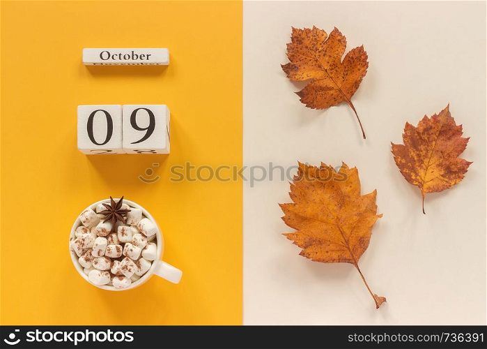 Autumn composition. Wooden calendar October 9 , cup of cocoa with marshmallows and yellow autumn leaves on yellow beige background. Top view Flat lay Mockup Concept Hello September.. Autumn composition. Wooden calendar October 9, cup of cocoa with marshmallows and yellow autumn leaves on yellow beige background. Top view Flat lay Mockup Concept Hello September