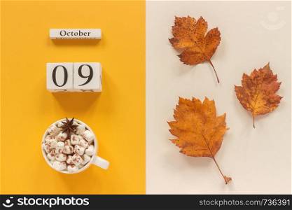 Autumn composition. Wooden calendar October 9 , cup of cocoa with marshmallows and yellow autumn leaves on yellow beige background. Top view Flat lay Mockup Concept Hello September.. Autumn composition. Wooden calendar October 9, cup of cocoa with marshmallows and yellow autumn leaves on yellow beige background. Top view Flat lay Mockup Concept Hello September