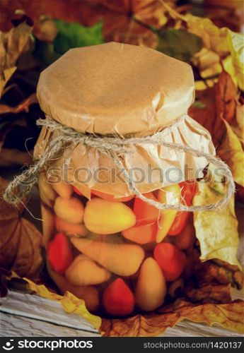 Autumn concept. Preserved food in glass jar on a wooden board. Marinated hot pepper. Autumn concept. Preserved food in glass jar