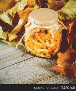 Autumn concept. Preserved food in glass jar on a wooden board. Marinated mushrooms. Autumn concept. Preserved food in glass jar