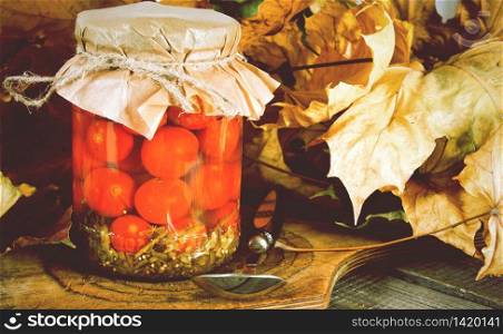 Autumn concept. Preserved food in glass jar on a wooden board. Marinated tomatoes. Autumn concept. Preserved food in glass jar