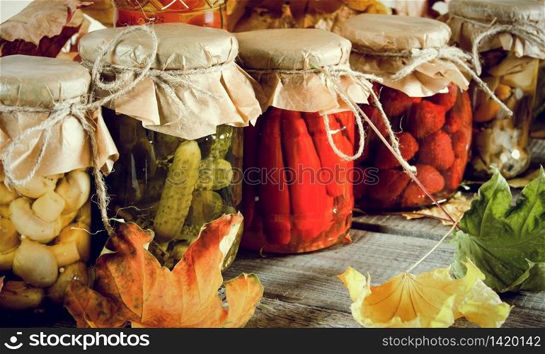 Autumn concept. Preserved food in glass jars on a wooden board. Marinated food. Autumn concept. Preserved food in glass jars