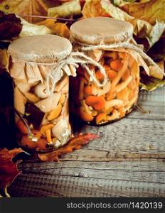Autumn concept. Preserved food in glass jars on a wooden board. Marinated mushrooms. Autumn concept. Preserved food in glass jars