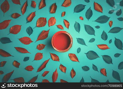 Autumn concept with green leaves painted in red using wood paint. Above view with colored leaves on a green background