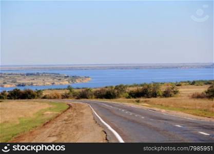 Autumn day landscape with empty road and blue river