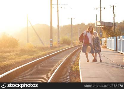 autumn day. mother and daughter are walking along the train waiting for the train