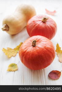 Autumn decorative pumpkins with fall leaves on wooden background. Thanksgiving or halloween holiday, harvest concept.