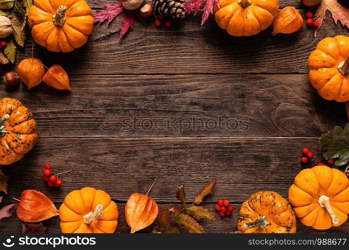 Autumn decorative pumpkins with fall leaves on wooden background. Thanksgiving or halloween holiday, harvest concept. Top view, copy space. Greeting card