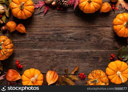 Autumn decorative pumpkins with fall leaves on wooden background. Thanksgiving or halloween holiday, harvest concept. Top view, copy space. Greeting card