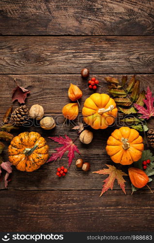 Autumn decorative pumpkins with fall leaves on wooden background. Thanksgiving or halloween holiday, harvest concept. Top view, copy space. Greeting card