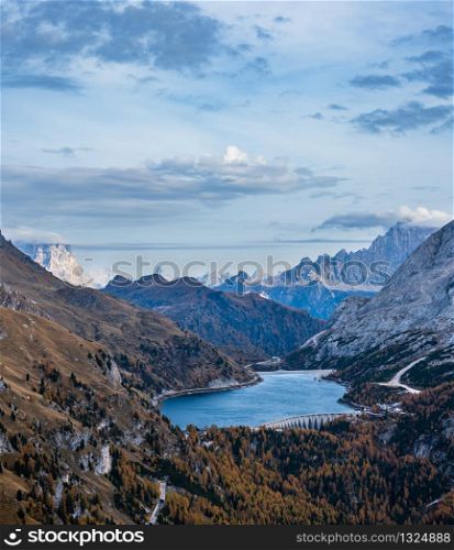 Autumn evening alpine Dolomites mountain scene from hiking path betwen Pordoi Pass and Fedaia Lake, Trentino, Italy. Snowy Marmolada Glacier and Fedaia Lake in far.