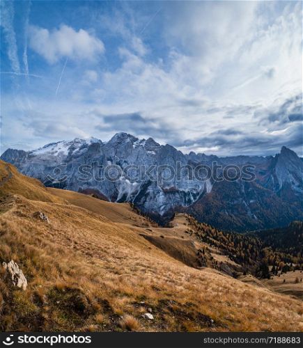 Autumn evening alpine Dolomites mountain scene from hiking path betwen Pordoi Pass and Fedaia Lake, Trentino, Italy. Snowy Marmolada massif and Glacier in far.