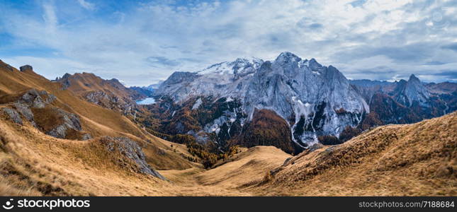 Autumn evening alpine Dolomites mountain scene from hiking path betwen Pordoi Pass and Fedaia Lake, Trentino, Italy. Snowy Marmolada Glacier and Fedaia Lake in far.