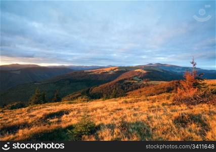 Autumn evening plateau landscape with lust golden sunlight on mountains and pink evening glow in sky
