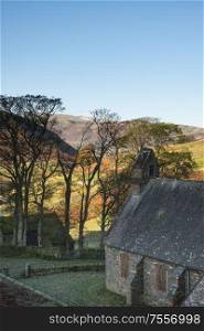 Autumn Fall landscape image of old abandoned church in Lake District with Sleet Fell in the background being lit by beautiful sunlight