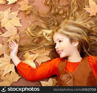 autumn fall little blond girl on dried tree leaves background and long spread hair
