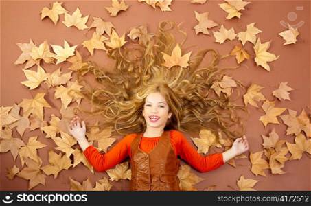 autumn fall little blond girl on dried tree leaves background and long spread hair