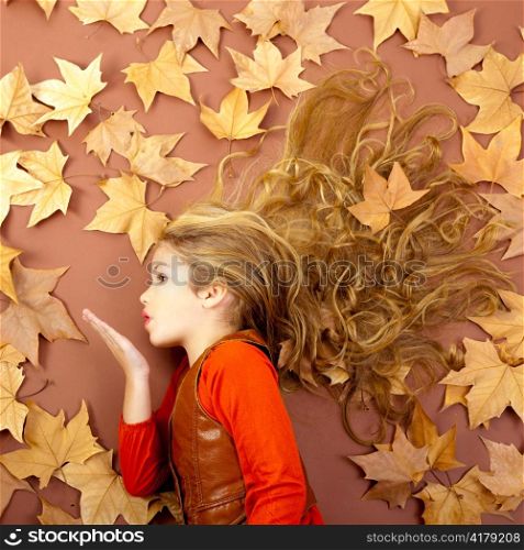 autumn fall little blond girl on dried tree leaves blowing wind with lips