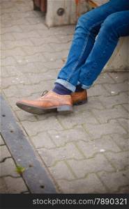 Autumn fashion, foot wear. Male legs in jeans and boots striped socks outdoor on street
