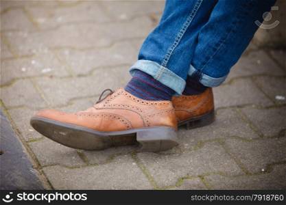 Autumn fashion, foot wear. Male legs in jeans and boots striped socks outdoor on street