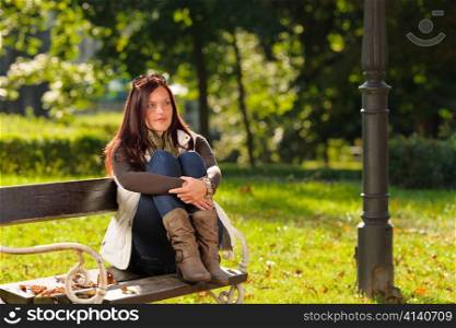 Autumn fashion outfit attractive woman sitting on park bench sunset