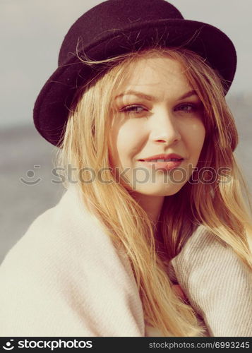 Autumn fashion. Woman wearing black fedora hat and sweater or long pink scarf, sea in background.. Woman wearing hat, sea in background