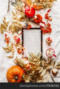 Autumn flat lay blank white letter board on white blanket decorated with fall arrangement: leaves, pumpkins, rowan ,burning candles and red cup of hot chocolate or coffee. Top view. Blog layout