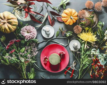 Autumn flowers arrangement preparation on dark table with candles, pumpkins and floral foam, top view